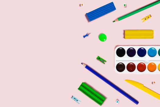 Back to school flat lay with colored pencils, watercolor, plasticine, and paper clips.