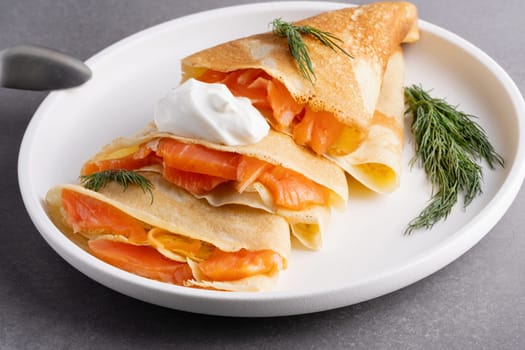 Pancakes with salmon, sour cream and greenstuff. Thin, not sweet blinchiki stuffed with red fish. Feast of Maslenitsa.