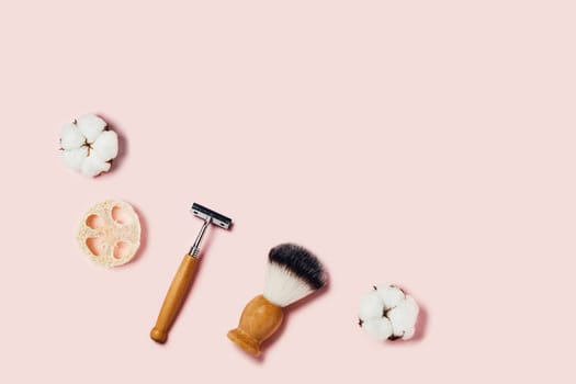 Bathroom accessories on pink background. Sponges, cotton flowers, shaving brush and razor. Flat lay, top view.