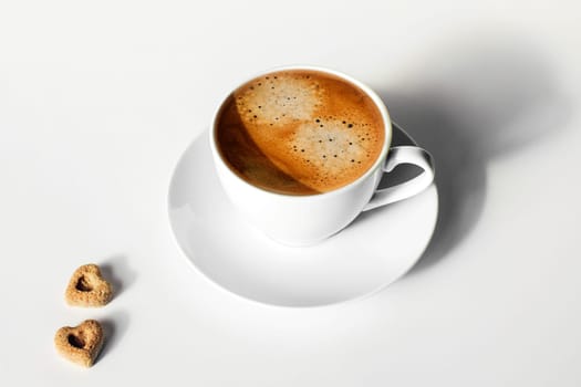 Cup of tasty espresso on white table with two peaces of sugar.