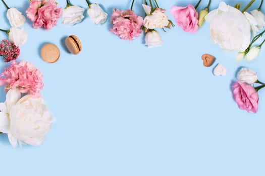Blue background with macaroons, peonies and roses. Top view with space for your text.