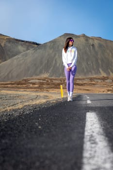 Woman wearing purple leggings on a road in Iceland