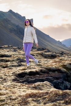 Woman with purple leggings walking in a lava field, Iceland