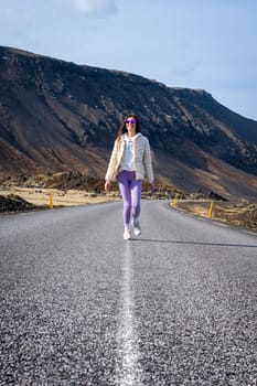 Woman wearing purple leggings on a road in Iceland