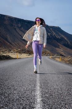 Woman running in wearing purple leggings on a road in Iceland