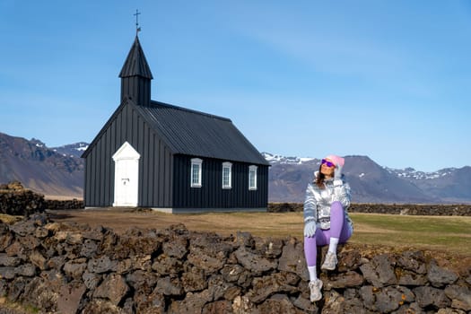 Woman with metallic coat in the black chapel of Budakirkja, Iceland