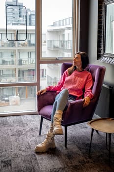 Woman sitting in an armchair next to a window