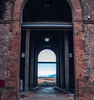 View from arched door looking out into the field photo. An arch through which you can see the backyard. Seen shady corners. Old brick wall texture background, Catalonia. High quality picture for wallpaper, article