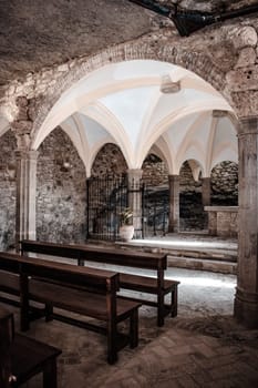 Rows of church benches, monastery in cliff. Sant Miquel del Fai is an 11th-century Benedictine monastery photo. Sunlight filtered through the stained glass window. High quality picture for wallpaper, article