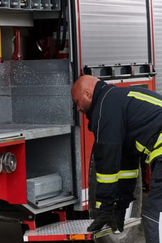A firefighter meticulously prepares a modern firetruck for a mission to evacuate and respond to dangerous situations, showcasing the utmost dedication to safety and readiness in the face of a fire emergency.