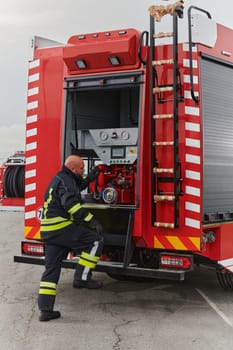 A firefighter meticulously prepares a modern firetruck for a mission to evacuate and respond to dangerous situations, showcasing the utmost dedication to safety and readiness in the face of a fire emergency.