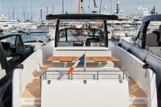 Close-up view of a relaxation area on the open teak deck of an expensive motorboat at sunny day, Monaco yacht show, large boat exhibition, wealth life, table and chairs. High quality photo