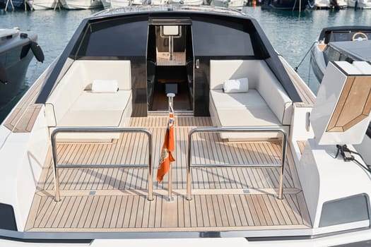 Close-up view of a relaxation area on the open teak deck of an expensive motorboat at sunny day, Monaco yacht show, large boat exhibition, wealth life, table and chairs. High quality photo