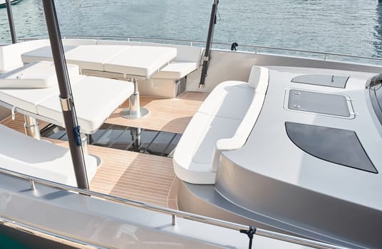 Close-up view of a relaxation area on the open teak deck of an expensive motorboat at sunny day, Monaco yacht show, large boat exhibition, wealth life, table and chairs. High quality photo