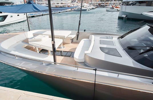 Close-up view of a relaxation area on the open teak deck of an expensive motorboat at sunny day, Monaco yacht show, large boat exhibition, wealth life, table and chairs. High quality photo