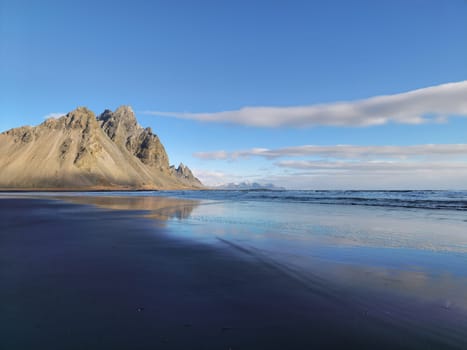 stokksnes black sand beach with vestrahorn mountain crest creating beautiful icelandic panorama. Majestic ocean beachfront coastline with hills on peninsula in wintry iceland.