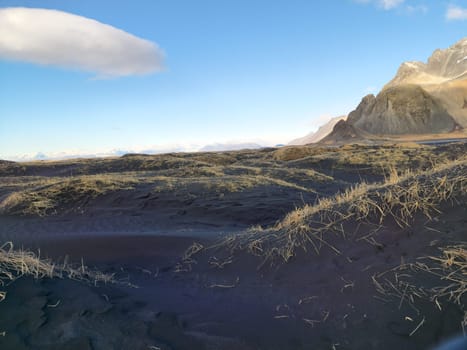 Northern region with black sand beach along shoreline and frozen Vestrahorn mountains range in Iceland. Spectacular Stokksnes beachfront with icelandic scenery and natural arctic skyline.