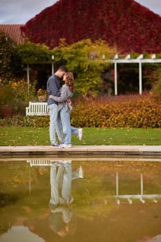 lovely young couple kissing outdoors in autumn. Loving couple walking in nature. Autumn mood. Happy man and woman hugging and kissing in autumn. Love. Fashionable couple outdoors. Fashion, people and lifestyle. Stylish couple in autumn outfit.