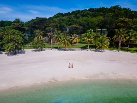 couple walking at the beach of Koh Kham Trat Thailand on a sunny day, men and woman on the beach drone aerial view