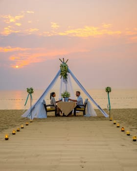 Romantic dinner on the beach in Pattaya Thailand, a couple man and woman mid age having dinner on the beach in Thailand during sunset with candles on the beach