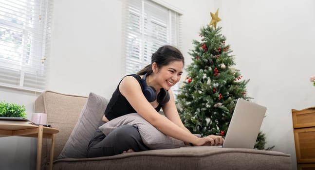 Young cheery happy positive cute beautiful business woman sit indoor in home using laptop computer.
