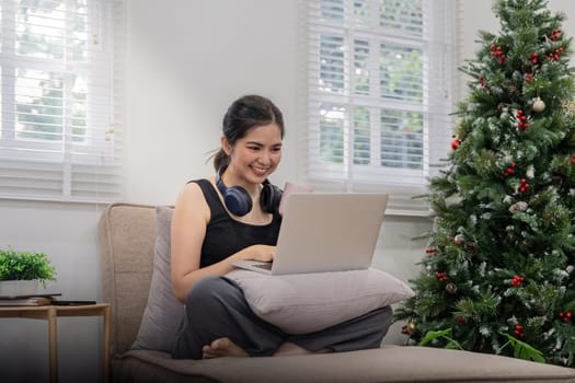 Young cheery happy positive cute beautiful business woman sit indoor in home using laptop computer.