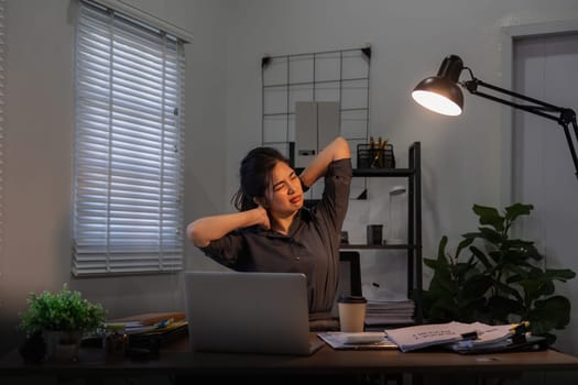 Asian business woman have a neck pain because using the laptop computer and working for a long time at night.