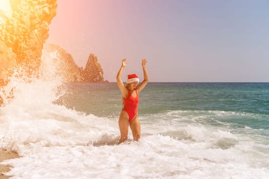 A woman in Santa hat on the seashore, dressed in a red swimsuit. New Year's celebration in a hot country