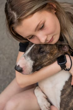 Portrait of caucasian woman hugging her bull terrier dog outdoors