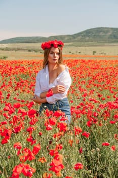 Happy woman in a poppy field in a white shirt and denim skirt with a wreath of poppies on her head posing and enjoying the poppy field