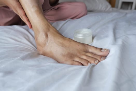 woman using petroleum jelly on feet at home .