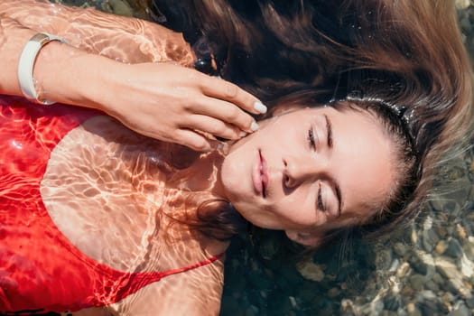 Side view a Young beautiful sensual woman in a mint long dress posing on a volcanic rock high above the sea during sunset. Girl on the nature on overcast sky background. Fashion photo