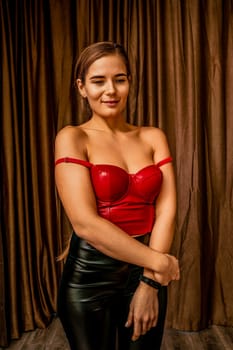 Young woman in red corset and black leather pants. Sexy brunette in red and black costume. Role play. Entertainment