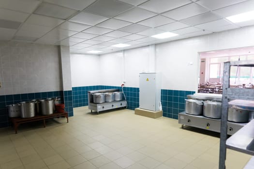 Industrial kitchen in school restaurant with professional equipment and pans