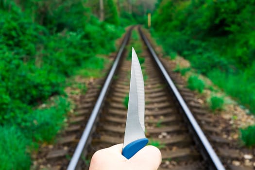 Knife in a hands on a rails, railroad