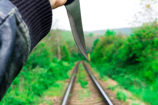 Knife in a hands on a rails, railroad