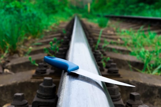 Knife in a hands on a rails, railroad