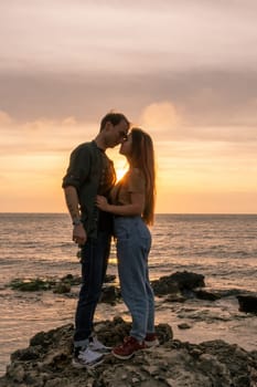 silhouettes in love romantic couple lovers hugging, kissing, touching, eye contact at sunset, sunrise on the background of the sea, the sun, the clouds in fiery red, orange colors.