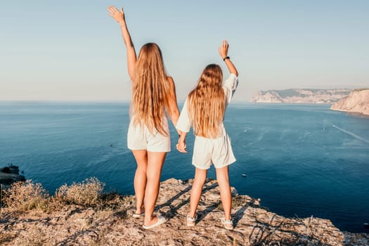 Close up portrait of mom and her teenage daughter hugging and smiling together over sunset sea view. Beautiful woman relaxing with her child.