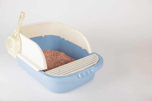 Promote cleanliness and hygiene with an isolated plastic cat litter toilet tray and scoop on a white background. A must-have for your pet's well-being.