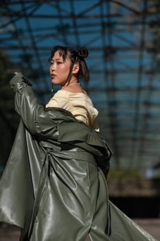 A beautiful Asian woman in shorts and a green leather coat comes out of the subway