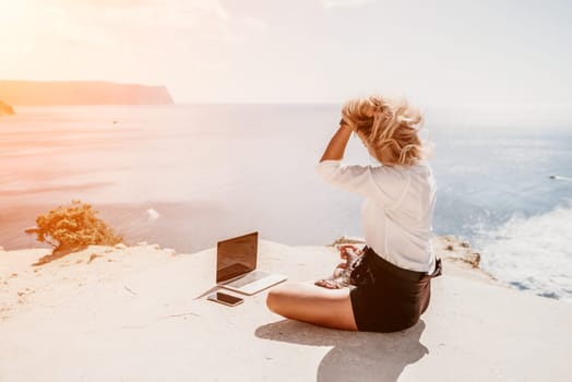 Happy girl doing yoga with laptop working at the beach. beautiful and calm business woman sitting with a laptop in a summer cafe in the lotus position meditating and relaxing. freelance girl remote work beach paradise