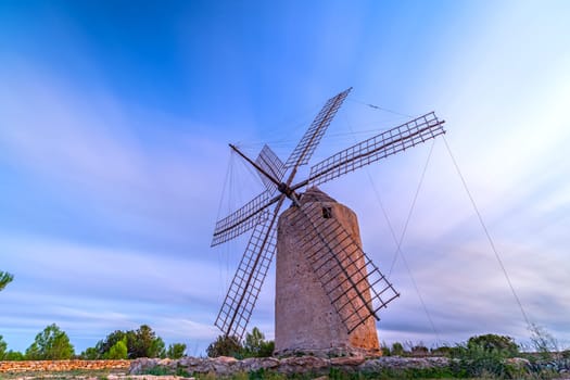 Old windmill ground view at sunset with silky clouds, warm pastel colors, ideal for text overlay.