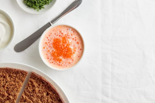 Homemade appetizer with red caviar, sour cream, dill, onion and rye bread on the white table - the traditional finnish recipe for a holiday food, flat lay in minimalistic style, healthy eating concept, horizontal with copy space