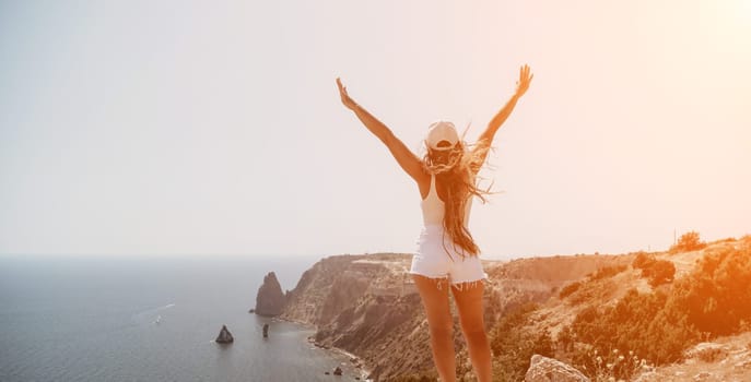 Woman travel sea. Young Happy woman in a long red dress posing on a beach near the sea on background of volcanic rocks, like in Iceland, sharing travel adventure journey