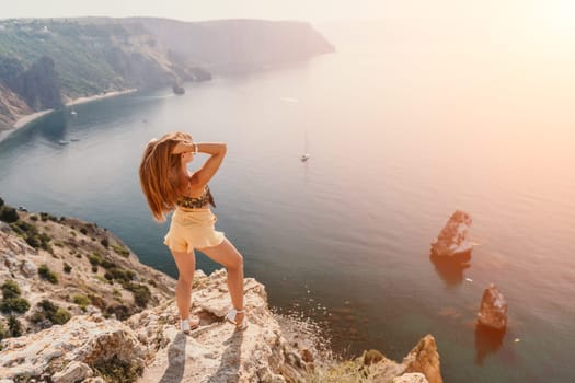 Woman travel sea. Happy tourist taking picture outdoors for memories. Woman traveler looks at the edge of the cliff on the sea bay of mountains, sharing travel adventure journey.