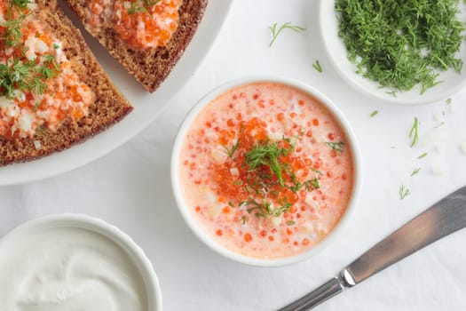 Homemade appetizer with red caviar, sour cream, dill, onion and rye bread on the white table - the traditional finnish recipe for a holiday food, flat lay in minimalistic style, healthy eating concept, horizontal