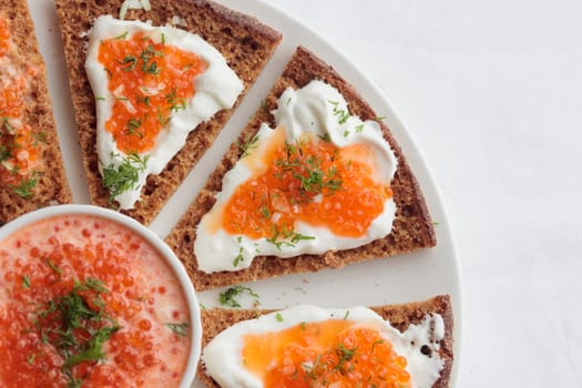 Homemade appetizer with red caviar, sour cream, dill, onion and rye bread on the white table - the traditional finnish recipe for a holiday food, flat lay in minimalistic style, healthy eating concept, horizontal