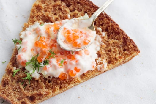 Homemade appetizer with red caviar, sour cream, dill, onion and rye bread on the white table - the traditional finnish recipe for a holiday food, flat lay in minimalistic style, healthy eating concept, horizontal