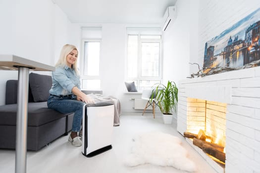 Woman relaxing at home with working air humidifier on the foreground. Concept of home air humidification.